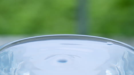 droplets of water splashing and splattering, creating ripples and small waves in a glass