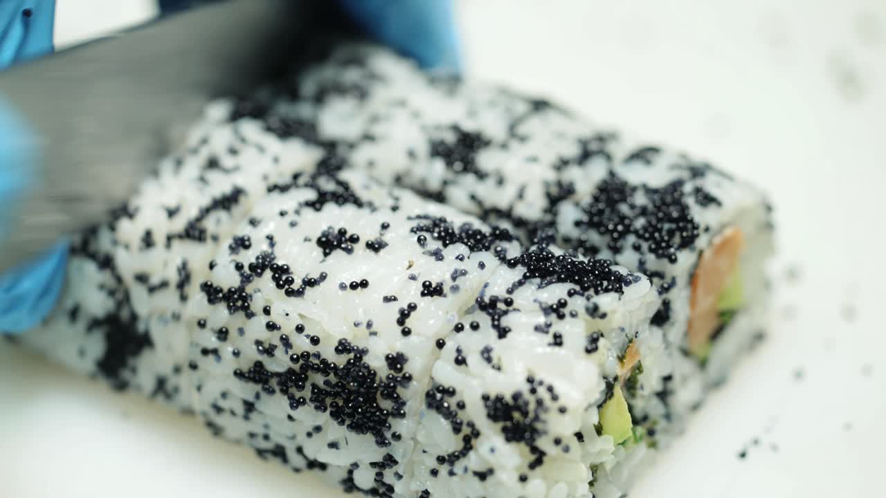 Chef in restaurant preparing and Cutting sushi rolls