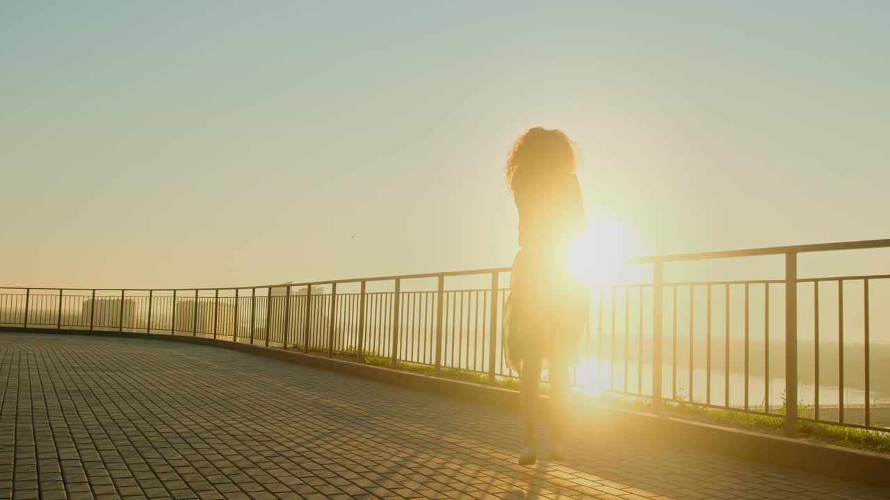 Woman enjoying sunset view from a city balcony