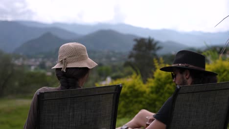 Man-and-woman-share-the-sunset-in-a-beautiful-mountain-landscape,-while-eating-and-drinking