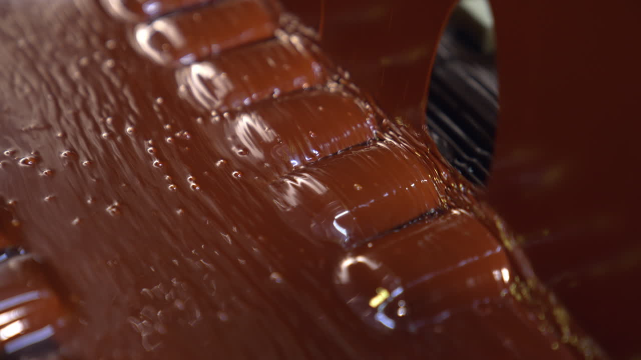 Candies come out from the flow of chocolate. Sweets deepened in a thick layer of chocolate. Close up.