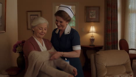 a nurse assists an elderly woman with dressing in a home setting