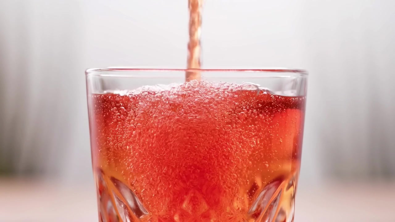 Red Carbonated Beverage Being Poured Into a Crystal Glass