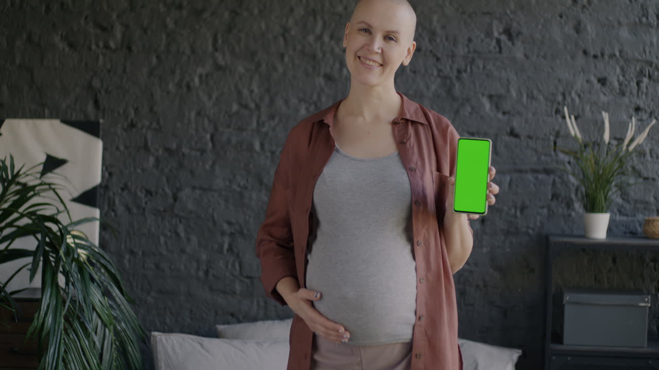Mulher grávida segurando telefone com tela verde
