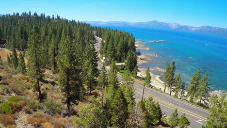 a rising aerial shot over a highway running along the shoreline of lake tahoe