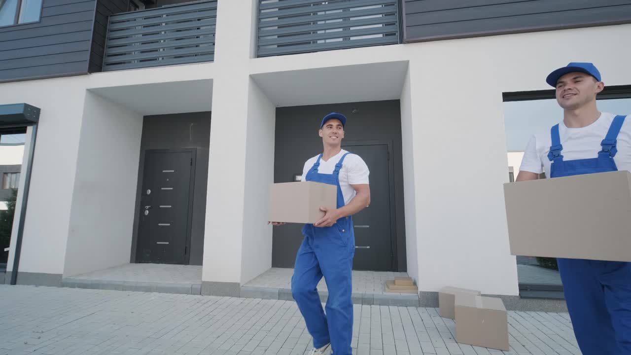 двое молодых работников перевозчиков загружают коробки и мебель в микроавтобус.