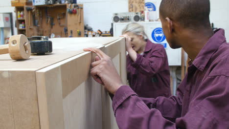 apprentices building furniture in carpentry workshop