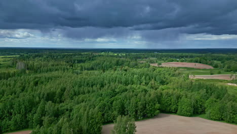 Exuberantes-árboles-Forestales-Verdes-Con-Nubes-Estratonimbus-Cuelgan-Sobre-El-Paisaje-Rural-De-Letonia-Desde-Un-Disparo-Aéreo-De-Drones