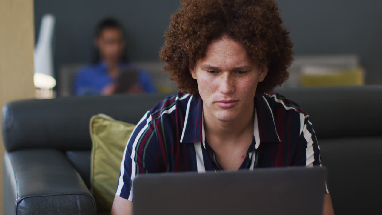 Caucasian man going through paperwork using a laptop in the office