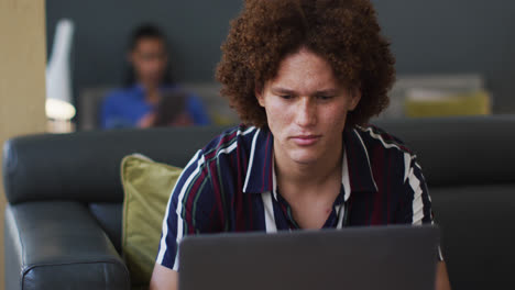 caucasian man going through paperwork using a laptop in the office