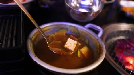 ladling kimchi soup into a bowl