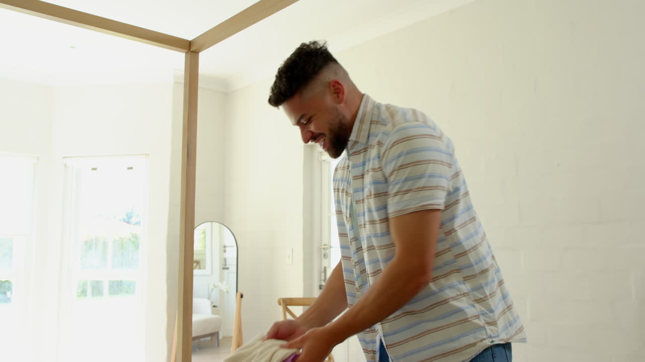 Hombre haciendo la maleta en casa, preparándose para las vacaciones familiares con entusiasmo.