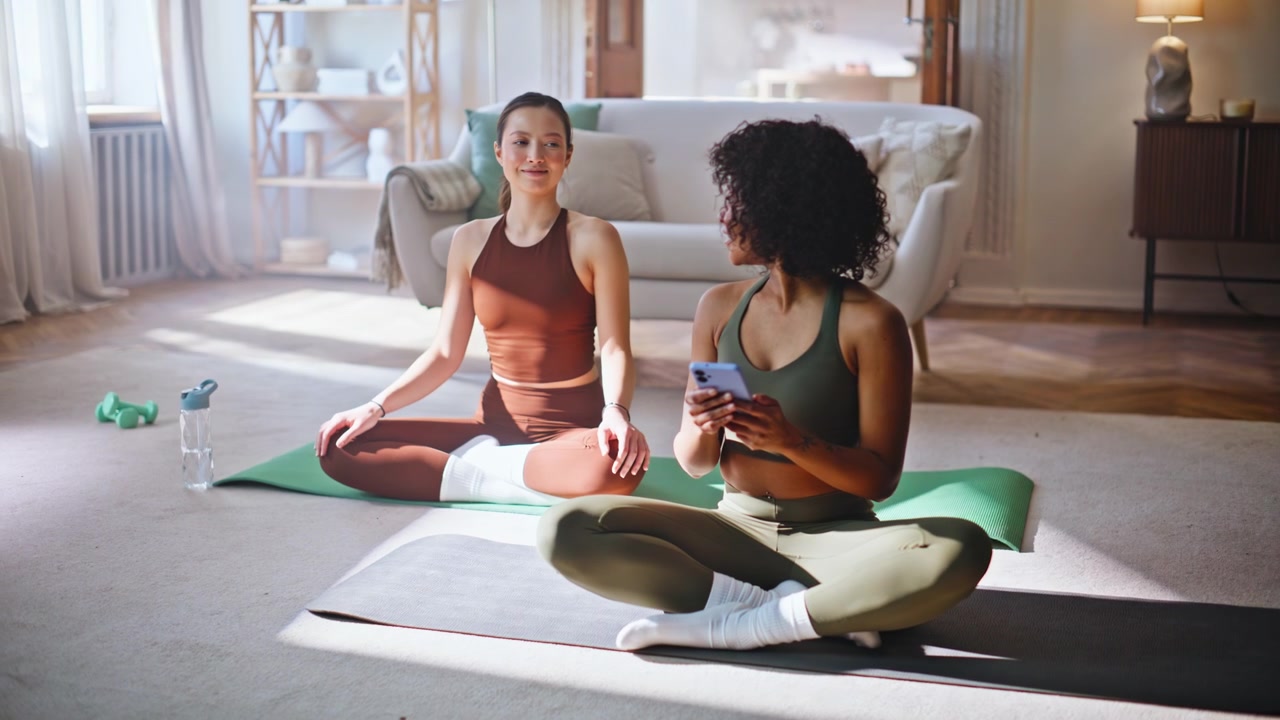 Kvinna tar upp telefonen under hemma-yogameditation med lugn partner i närheten