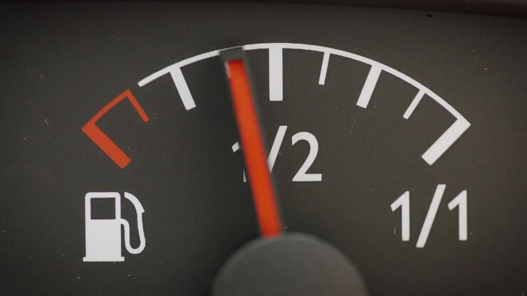 Macro horizontal view of a vehicle dashboard fuel gauge with the needle pointing towards the full mark, symbolizing successful refueling or preparation for a road trip