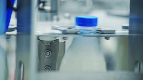 robotic machine of twisting lid on a plastic bottle. automated process of putting cover on a bottle with milk in a modernized diary plant. close-up.