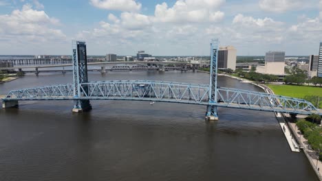 boat cruising under main street, john t alsop, bridge in jacksonville florida viewed from off-center stationary drone