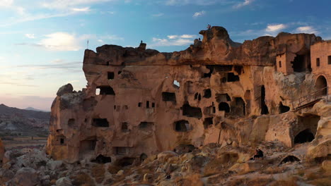 Ancient-stone-carved-homes,-Cavusin-village,-wide-pan-shot-over-Cappadocia,-Turkey