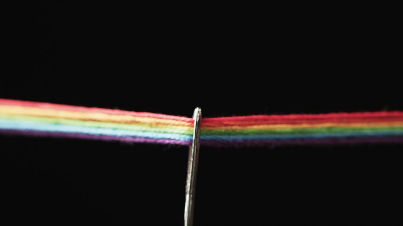 video de micro de hilos de color arco iris que pasan a través de la aguja con espacio de copia en fondo negro