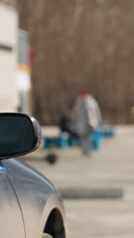 vista cercana de las ramas de los árboles en un estacionamiento urbano con edificios de la ciudad en el fondo, con una vista bokeh de alguien que viene
