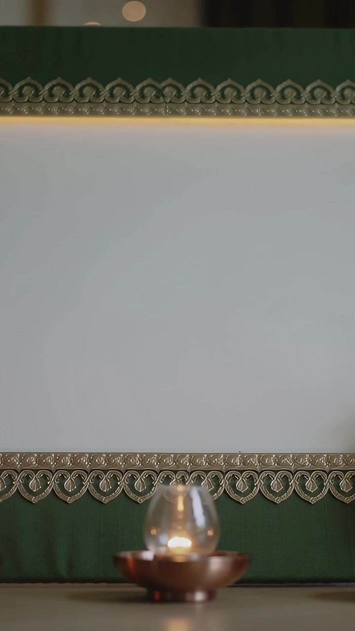 Vertical video: Flickering glass votive candle revealing white panel during pullback, green trim