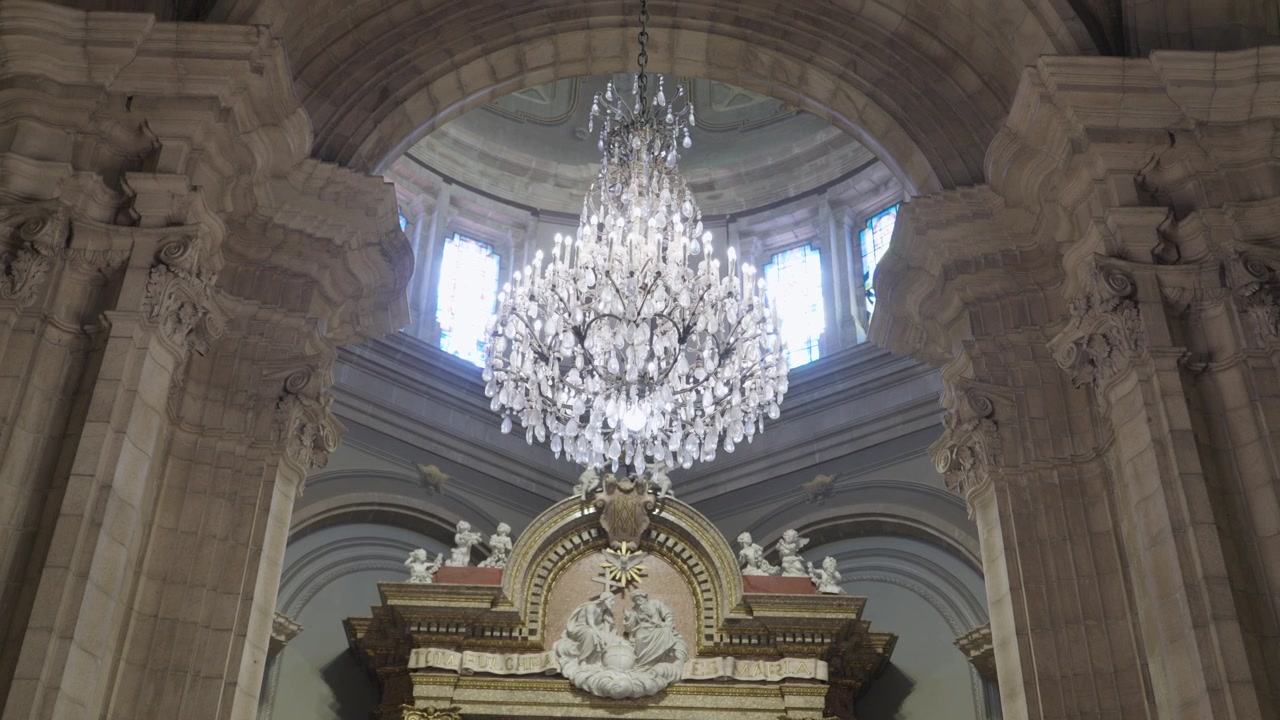 Grande lampadario di cristallo sotto un soffitto a cupola sopra una pala d'altare intagliata in una chiesa.