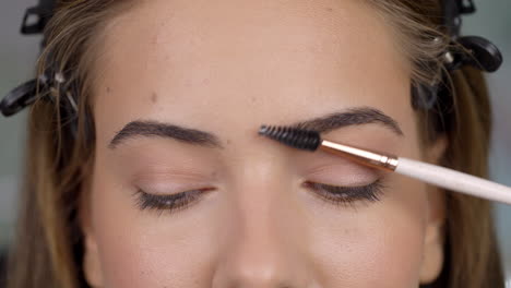 close-up of a person styling their eyebrows with a brush