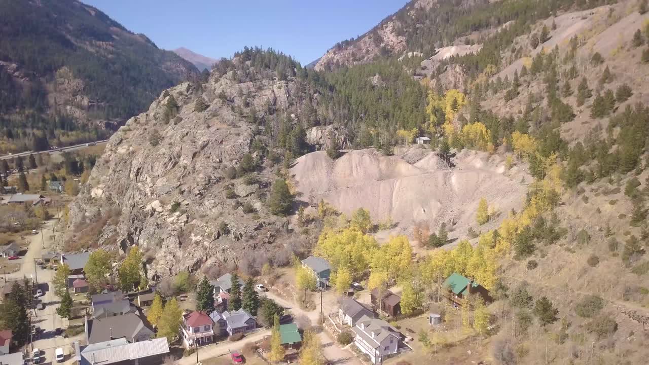 un pequeño pueblo de montaña con una ladera con álamos y cielos azules