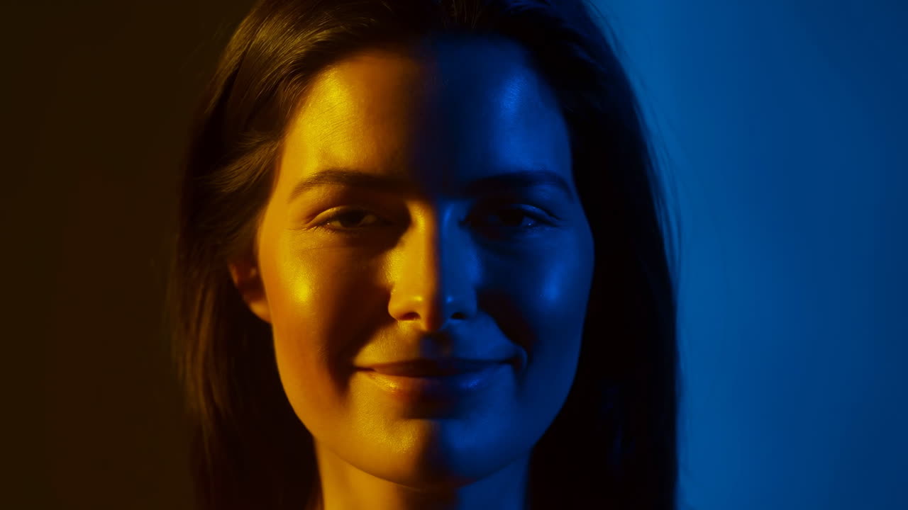 Ritratto in studio diviso blu ambra di una modella in posa sotto un'illuminazione drammatica, l'inquadratura ravvicinata cattura sottili