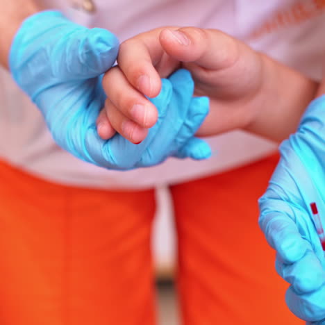 female nurse taking blood into vial. hands in sterile blue gloves of a medical worker collect blood from patient's finger. close-up.