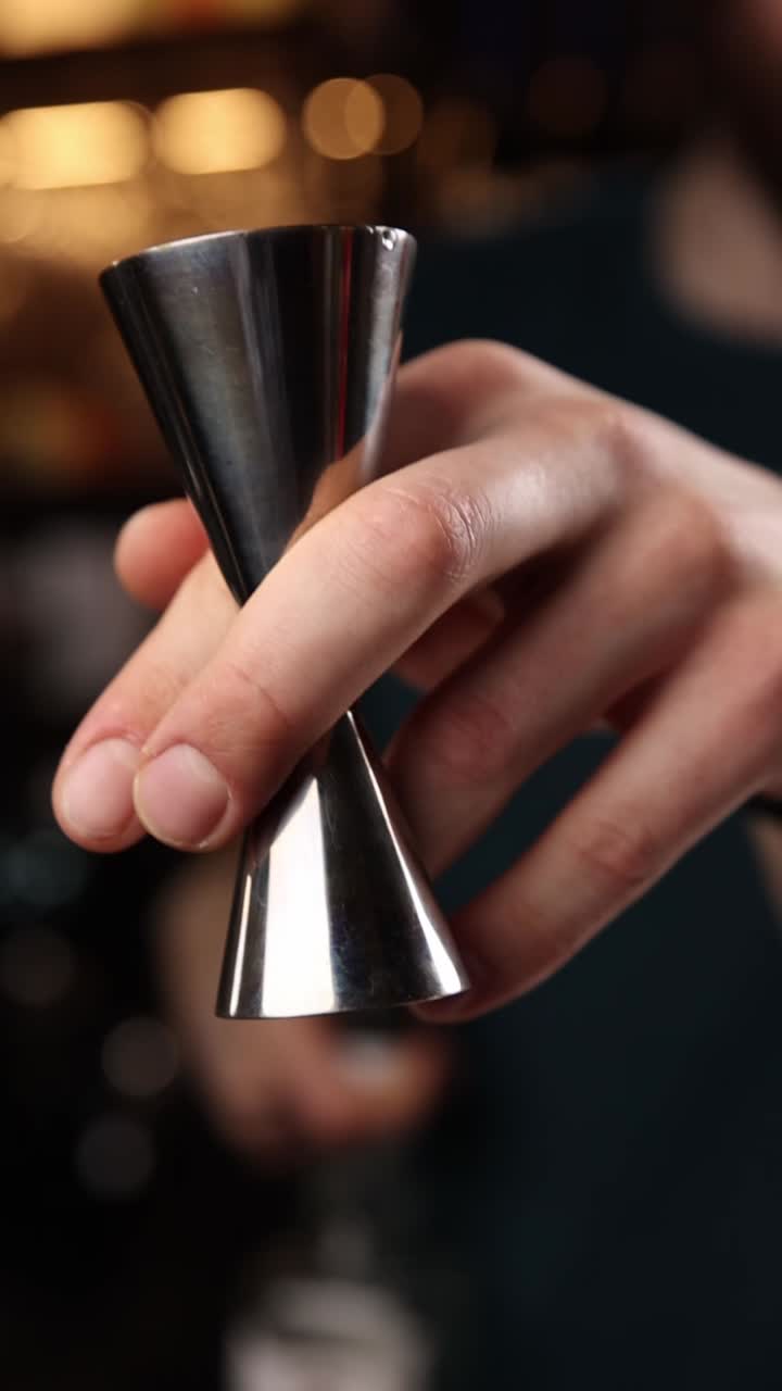 Un barista versa alcolici con un jigger