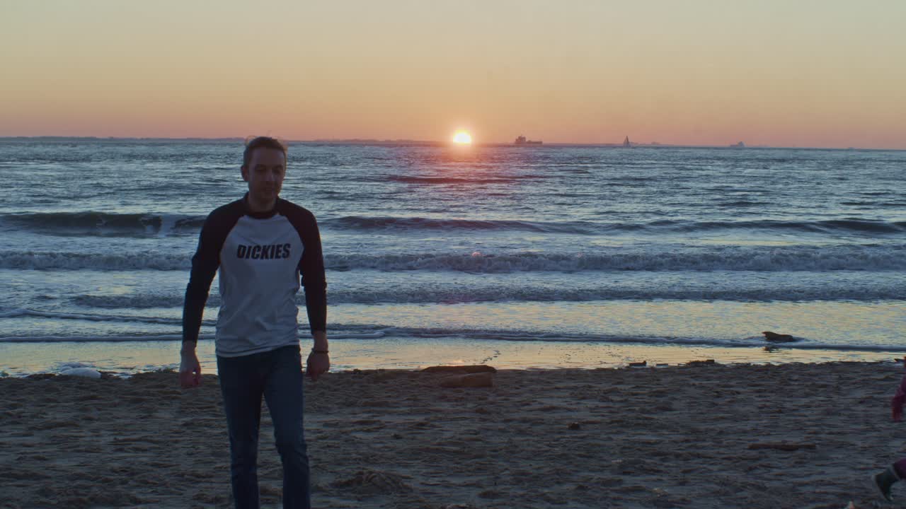 kaukasische mannelijke man model en kind kind lopen lopen op het strand bij de zee oceaan op de zandkust met zonsondergang
