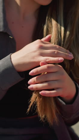 primer plano de una mujer con una camiseta negra bajo una camisa gris, tocando su cabello lúdicamente, con una vista parcial de la bolsa de compras roja es visible a su lado con el fondo ligeramente borroso