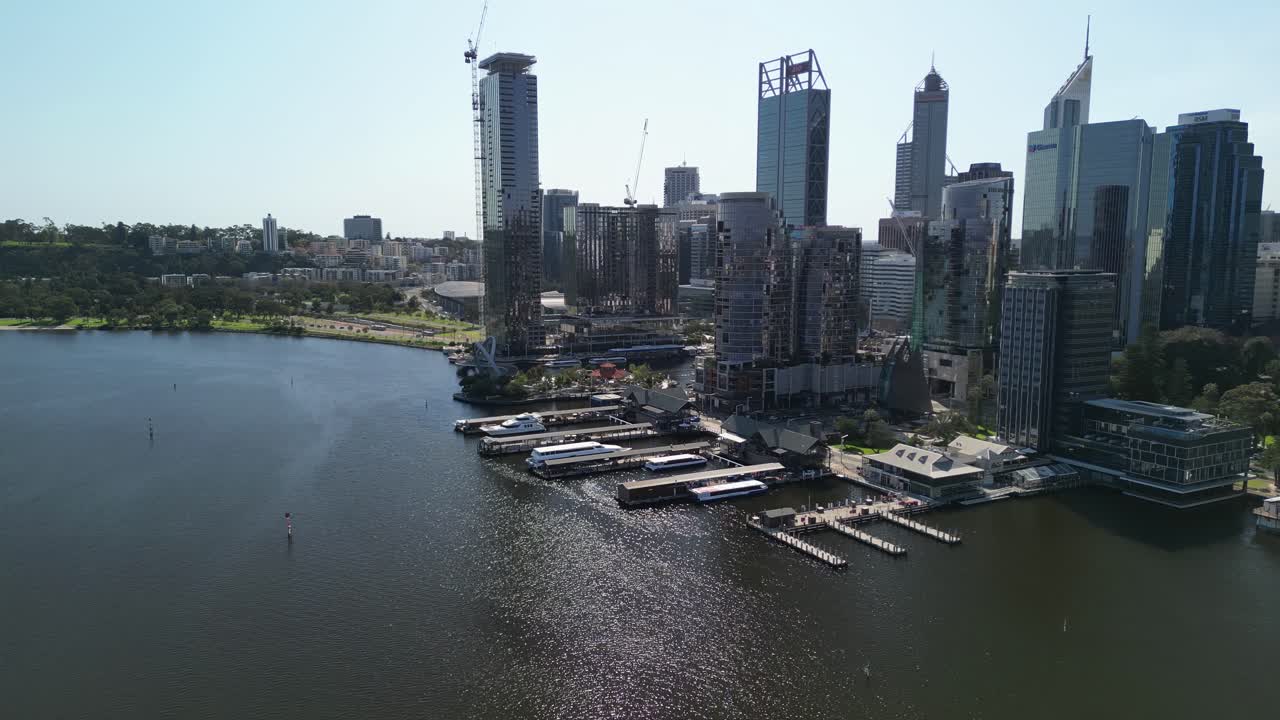 Ripresa aerea in avvicinamento dello skyline di Perth con il porto sul fiume Swan durante una giornata di sole - Cantiere con gru in funzione su un grattacielo in città.