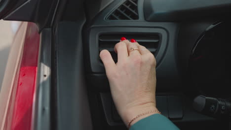 female driver adjusts air conditioner in car to cool salon