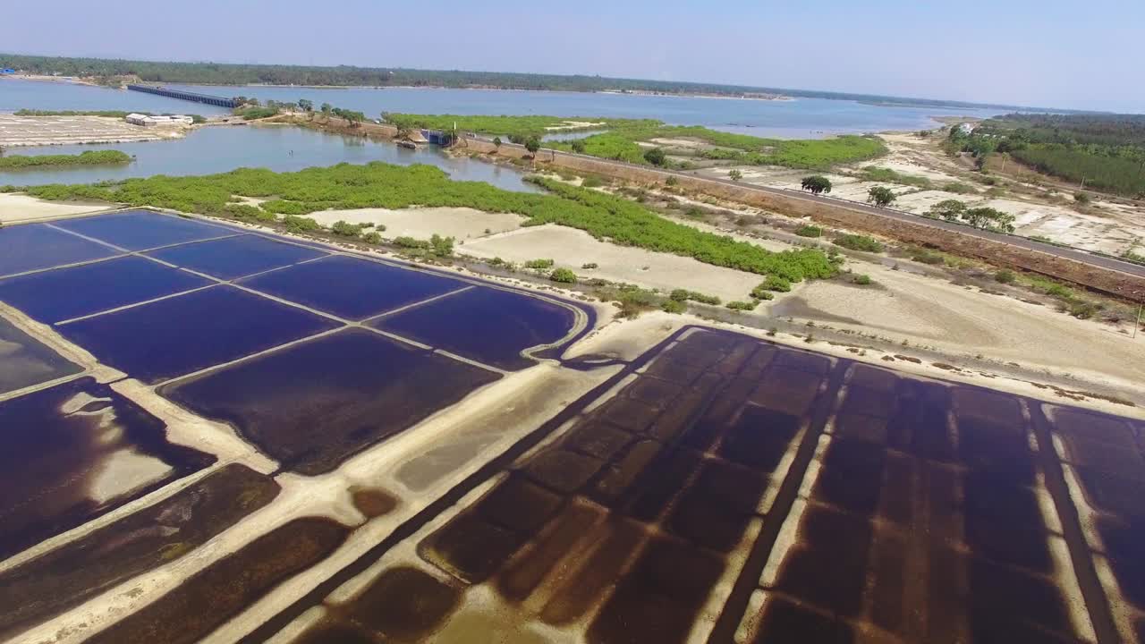 imágenes de drones moviéndose hacia adelante y hacia abajo a través de una salina con la carretera de la costa este, india, al fondo