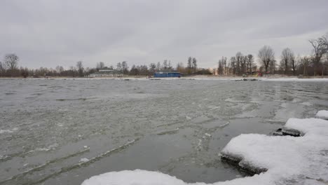 Eis-Schwimmt-Auf-Einem-Zugefrorenen-See-Mit-Strand-Im-Hintergrund