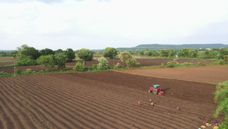 agricultural field with tractor and people working