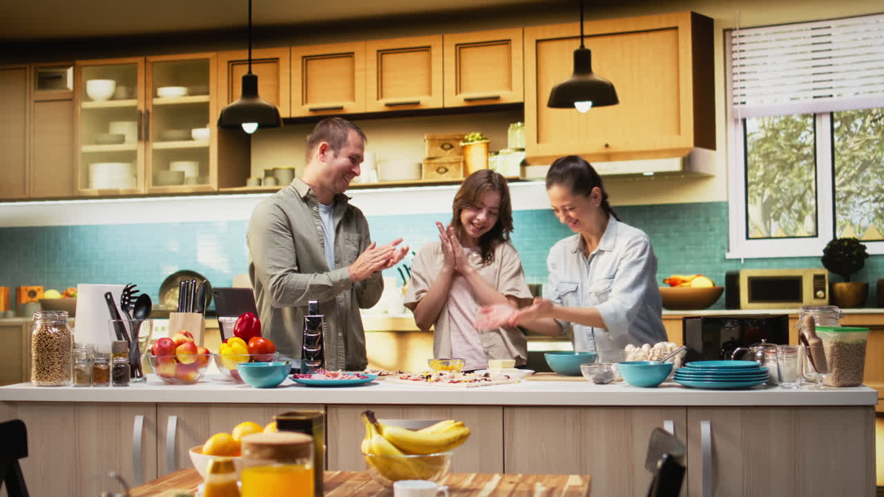 Family clapping hands after making delicious homemade pizza together