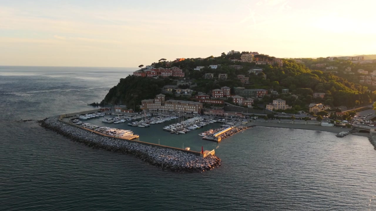 Vista aerea della marina di Arenzano e degli edifici collinari nella calda luce del tramonto, costa ligure.