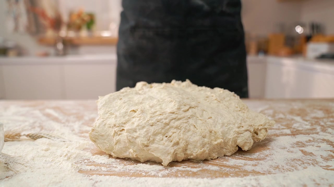 Panettiere posiziona l'impasto crudo su una superficie di legno infarinata