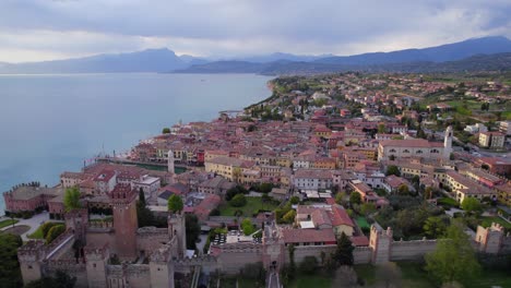 Drone-Volando-Sobre-El-Pintoresco-Pueblo-Medieval-Italiano-De-Lazise-En-La-Orilla-Del-Lago-De-Garda-Al-Atardecer