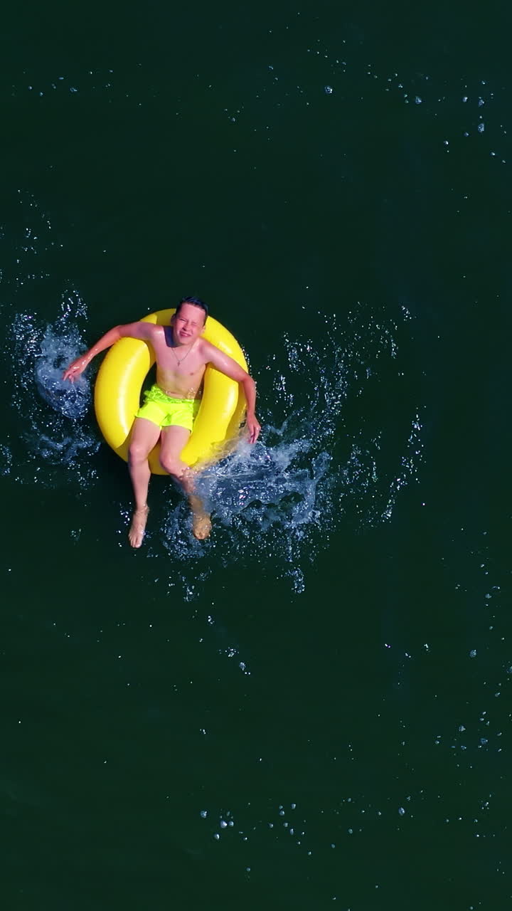 Boy swimming on pool ring. Top down view of boy floating on swim ring