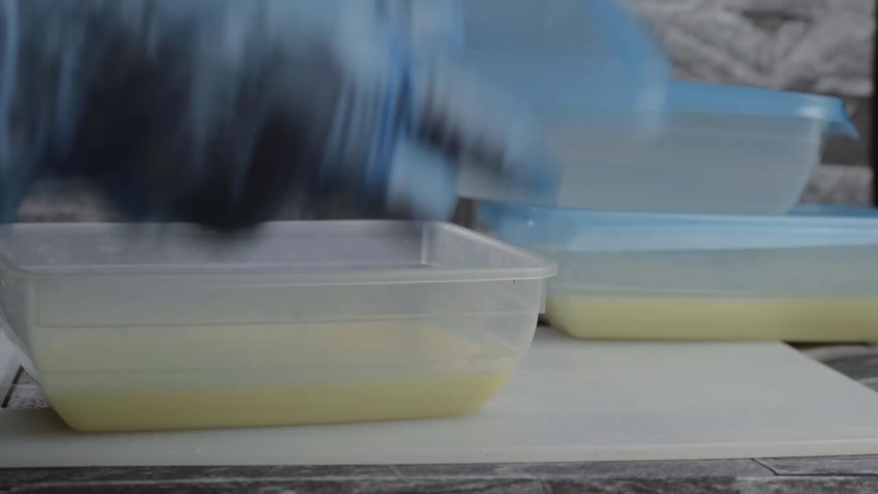 Hand wearing hygiene gloves putting food into a plastic storage container