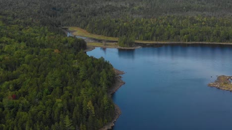 aerial footage of a remote lake in northern maine zooming in towards lake inlet with forest and mountains in background