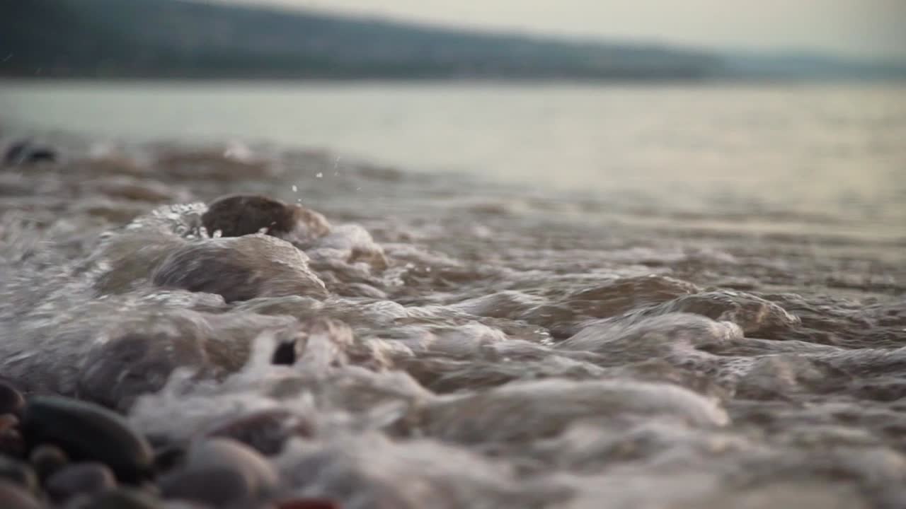 calm small waves crashing into rocks on a beach low close up slow motion