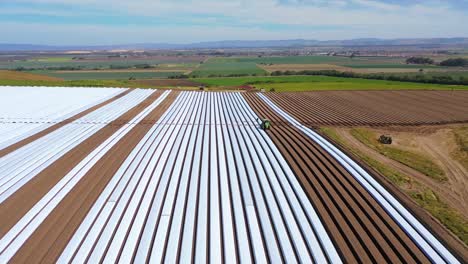 antena de tractores colocando filas de cubiertas de plástico en campos agrícolas cerca de santa maría california 1