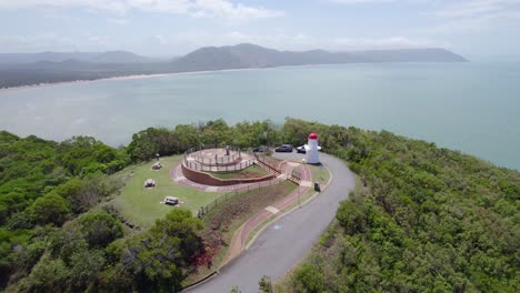 Frondosos-árboles-Verdes-Alrededor-Del-Mirador-De-La-Colina-Cubierta-De-Hierba-Y-La-Luz-De-Cooktown-Con-Vistas-Al-Mar-Azul-En-Calma-En-Australia