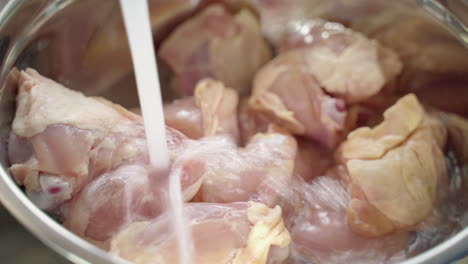 un primerísimo plano de un tazón de pollo crudo que se enjuaga