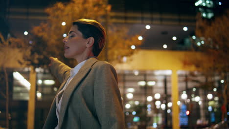 Mujer-Tomando-Un-Taxi-En-El-Centro-Por-La-Noche.-Una-Mujer-De-Negocios-Relajada-Y-Tardía-Viaja-A-Casa