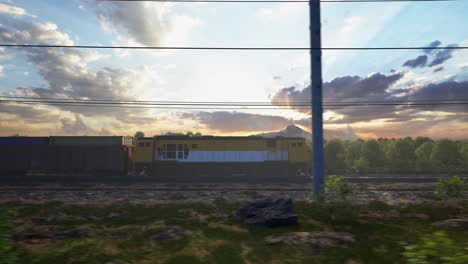a freight train hauls shipping containers through the landscape, sunset and blue sky
